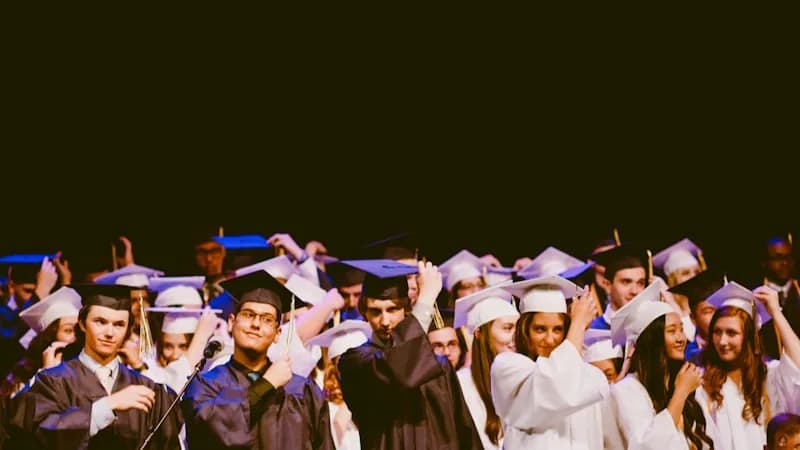 Formandos em cerimônia de formatura com becas e capelo